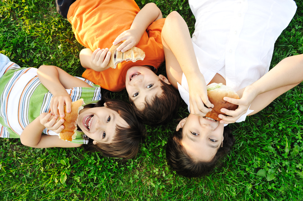 Kids laying in grass eating food